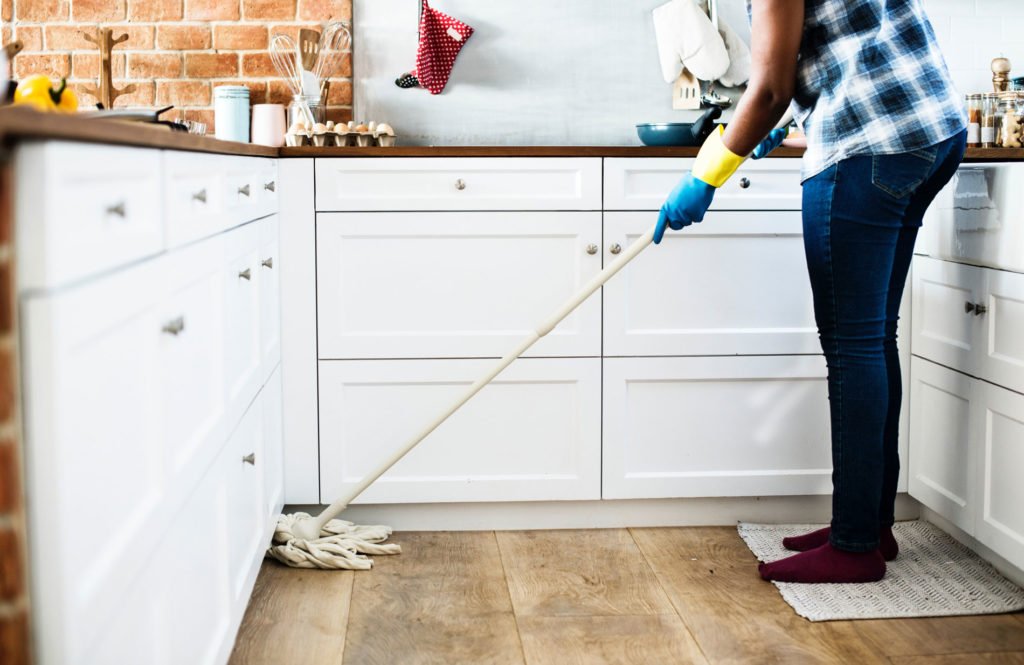 person cleaning kitchen floor with mop
